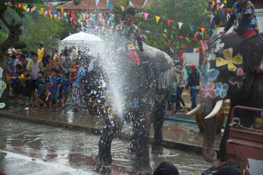 AYUTTHAYA , THAILAND - APRIL13, 2018: Elephants are using their trunks to spray water for Thai people and foreign tourists having fun. During the Songkran Festival, the traditional Thai New Year Day . At the Naresuan road in Ayutthaya city ,Thailand.