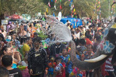 AYUTTHAYA , THAILAND - APRIL13, 2018: Elephants are using their trunks to spray water for Thai people and foreign tourists having fun. During the Songkran Festival, the traditional Thai New Year Day . At the Naresuan road in Ayutthaya city ,Thailand.