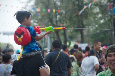 AYUTTHAYA, THAILAND - APRIL13, 2018 : An unidentified little boy rides on his father's neck playing water spray with plastic gun. Join in on the Songkran Festival, the traditional New Year celebration from April 13 to 15 in Ayutthaya , Thailand.