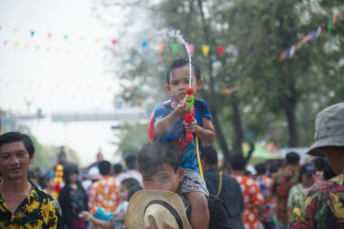 AYUTTHAYA, THAILAND - APRIL13, 2018 : An unidentified little boy rides on his father's neck playing water spray with plastic gun. Join in on the Songkran Festival, the traditional New Year celebration from April 13 to 15 in Ayutthaya , Thailand.