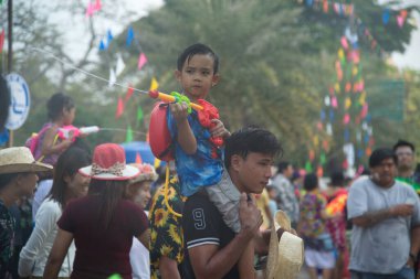 AYUTTHAYA,THAILAND - APRIL13, 2018 : Unidentified little boy and girl rides on his father's neck playing water spray with plastic gun. Join in on the Songkran Festival, the traditional New Year celebration from April 13 to 15 in Ayutthaya , Thailand.