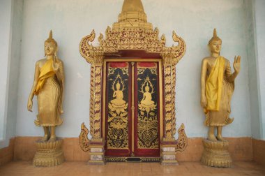 Traditional Thai art pattern made of wood and two Buddhas decorated at the Thai Church door at Wat Somdet, a historic site in Amphoe Sangkhlaburi, Kanchanaburi Province , Middle of Thailand. 