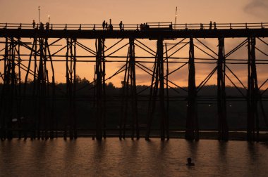 KANCHANABURI ,THAILAND - APRIL 16 , 2016 : Mon Bridge or Uttamanusorn Bridge in silhouette is a wooden bridge used to cross the Songkhlalia river to Mon village at Sangkhlaburi. that is 445 meters long. Located Sangkhlaburi, Kanchanaburi, Thailand.
