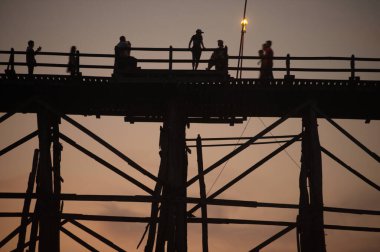 KANCHANABURI ,THAILAND - APRIL 16 , 2016 : Mon Bridge or Uttamanusorn Bridge in silhouette is a wooden bridge used to cross the Songkhlalia river to Mon village at Sangkhlaburi. that is 445 meters long. Located Sangkhlaburi, Kanchanaburi, Thailand.