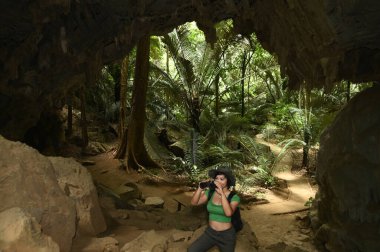 Güzel bir Asyalı kadın, bir Hup Pa Tat mağarasının girişindeki dürbünle bakar ve Taylandlı turistler için popüler bir turistik cazibe..