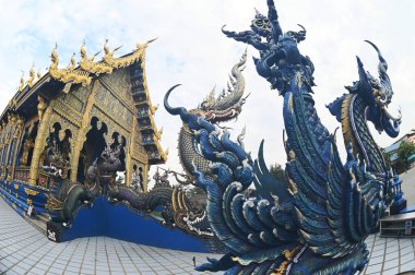 Kilisenin önündeki Naga Merdiven Heykeli, mavi ve gökyüzünün tonlarını altınla zıtlaştıran eşsiz bir sanat eseridir. Çeşitli desenler akar ve hassastır. Wat Rong Suea 10 tapınağında. Tayland 'ın Chiang Rai Eyaleti' nde..