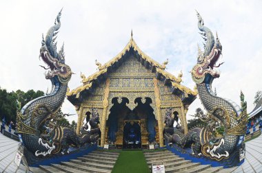 Kilisenin önündeki Naga Merdiven Heykeli, mavi ve gökyüzünün tonlarını altınla zıtlaştıran eşsiz bir sanat eseridir. Çeşitli desenler akar ve hassastır. Wat Rong Suea 10 tapınağında. Tayland 'ın Chiang Rai Eyaleti' nde..