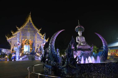 Phra Upakut 'un gece sahnesi nilüfer çiçeklerinin gölgesinin altındaki çeşmenin ortasına yerleştirilmiş inci beyazı bir heykeldir. Wat Rong Suea 10 tapınağındaki kilisenin önünde. Tayland 'ın Chaing Rai bölgesinde yer almaktadır..