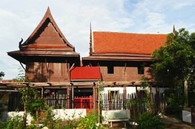 Bahçe süslemeli Tayland tarzı ahşap ev ve Wat Phra Non Chakkasi Worawihan tapınağının içini göster. Tayland 'ın Ratchaburi eyaletinde yer almaktadır..