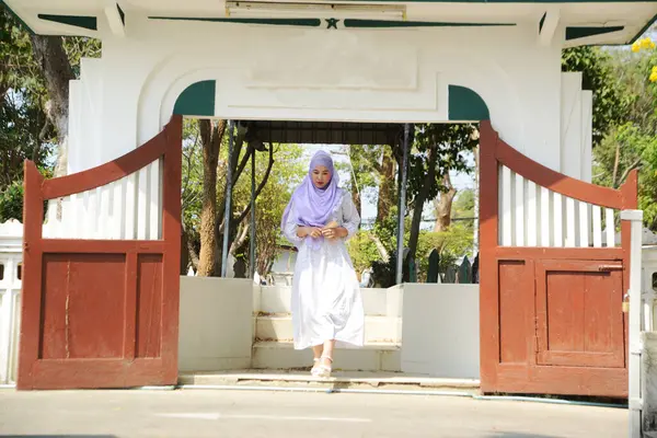 Pretty Asian woman wearing hijab walking from a tomb.