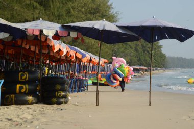 PHETCHABURI, THAILAND - 9 HAZİRAN 2024: Kimliği belirlenemeyen Asyalı bir erkek turistlere günlük olarak hizmet etmek üzere denizde plastik bir yüzme tüpü taşıyor.