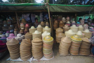 PYAY, MYANMAR - 11 DEC 2018: İskelede Akauk Taung 'a çeşitli şapkalar satan kimliği belirsiz bir satıcı Htonbo köyü yakınlarındaki Akauk Dağı uçurumunda oyulmuş bir Buda resmine sahip. Magway Bölgesi.