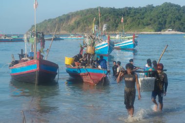 Teşekkürler, MYANMAR - 10 Aralık 2018: Ngapali sahilindeki bir balıkçı köyünde kimliği belirsiz bir köylü elinde plastik bir sepetle balık taşıyor. Rakhine eyaletinin Bengal Körfezi 'nde yer almaktadır..