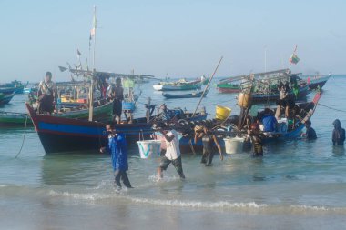 TEŞEKKÜRLER, MYANMAR - 10 Aralık 2018: Ngapali sahilindeki bir balıkçı köyünde, kimliği belirsiz bir köylü omzunda plastik bir sepetle balık taşıyor. Rakhine eyaletinin Bengal Körfezi 'nde yer almaktadır..