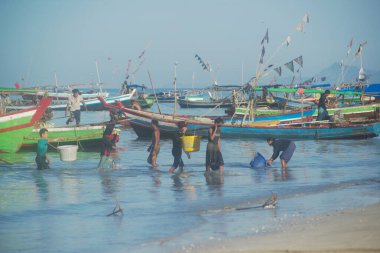 TEŞEKKÜRLER, MYANMAR - 10 Aralık 2018: Ngapali sahilindeki bir balıkçı köyünde, kimliği belirsiz bir köylü omzunda plastik bir sepetle balık taşıyor. Rakhine eyaletinin Bengal Körfezi 'nde yer almaktadır..