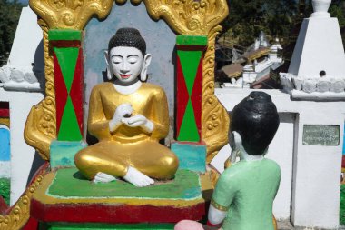 An outdoor statue of a Burmese Buddhist woman paying homage to Buddha adorns front of the chapel or Buddhist church at Wat Mahamuni Phraya temple. It is located on the Rakhine State, Myanmar. clipart