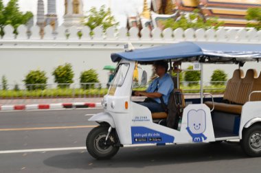 BANGKOK, THAILAND - 28 Ağustos 2024: kimliği belirsiz bir adam tuk tuk kullanıyor. Wat Phra Kaew civarına yolcu bırakın. Burası önemli bir yer. Bu tür bir araç popüler bir ulaşım şeklidir..