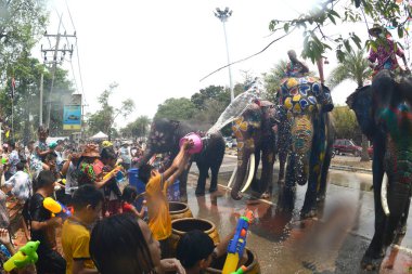 AYUTTHAYA, THAILAND -13 Nisan 2024: Tanımlanamayan turistler ve Taylandlılar plastik tabanca veya kase kullanarak fillere su sıçratmada birleşiyorlar. Tayland 'daki Ayutthaya Tarih Parkındaki Songkran Festivali' nde iyi eğlenceler..