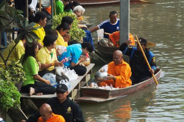 SAMUT SONGKHRAM, Tayland - 11 Aralık 2023: Amphawa Yüzen Pazar alanı ve topluluk, su yoluyla sadaka verme geleneğini yeniden canlandırdı. Bu, Amphawa Kanalı 'ndaki insanların eski bir geleneği olarak kabul edilir..