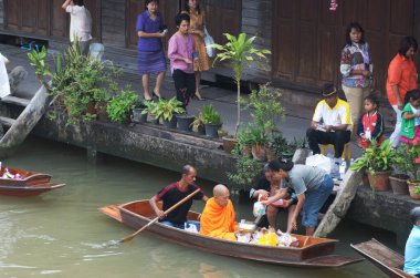 SAMUT SONGKHRAM, Tayland - 11 Aralık 2023: Amphawa Yüzen Pazar alanı ve topluluk, su yoluyla sadaka verme geleneğini yeniden canlandırdı. Bu, Amphawa Kanalı 'ndaki insanların eski bir geleneği olarak kabul edilir..