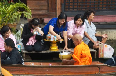 SAMUT SONGKHRAM, Tayland - 11 Aralık 2023: Amphawa Yüzen Pazar alanı ve topluluk, su yoluyla sadaka verme geleneğini yeniden canlandırdı. Bu, Amphawa Kanalı 'ndaki insanların eski bir geleneği olarak kabul edilir..