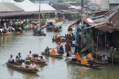 SAMUT SONGKHRAM, Tayland - 11 Aralık 2023: Amphawa Yüzen Pazar alanı ve topluluk, su yoluyla sadaka verme geleneğini yeniden canlandırdı. Bu, Amphawa Kanalı 'ndaki insanların eski bir geleneği olarak kabul edilir..