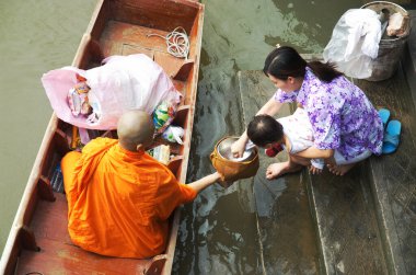 SAMUT SONGKHRAM, Tayland - 11 Aralık 2023: Amphawa Yüzen Pazar alanı ve topluluk, su yoluyla sadaka verme geleneğini yeniden canlandırdı. Bu, Amphawa Kanalı 'ndaki insanların eski bir geleneği olarak kabul edilir..