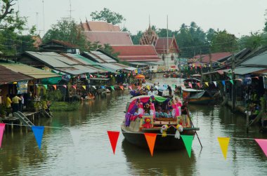 SAMUT SONGKHRAM, Tayland - 11 Aralık 2023: Amphawa Yüzen Pazar alanı ve topluluk, su yoluyla sadaka verme geleneğini yeniden canlandırdı. Bu, Amphawa Kanalı 'ndaki insanların eski bir geleneği olarak kabul edilir..