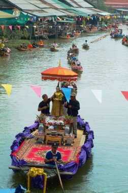 SAMUT SONGKHRAM, Tayland - 11 Aralık 2023: Amphawa Yüzen Pazar alanı ve topluluk, su yoluyla sadaka verme geleneğini yeniden canlandırdı. Bu, Amphawa Kanalı 'ndaki insanların eski bir geleneği olarak kabul edilir..