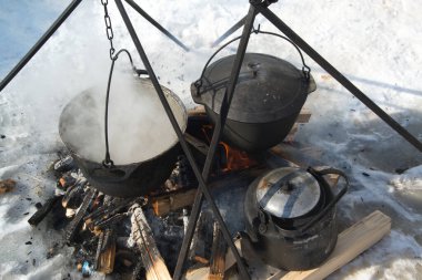 Kışın Baykal Gölü 'nde kamp yaparken balık çorbası pişirmek için kullanılan bir tencere. Yerel balıkçı, Kuzey ve Güney Olkhon Adası, Sibirya, Rusya 'daki sıcak taş ve kömürlerin yardımıyla ateşte pişirildi..