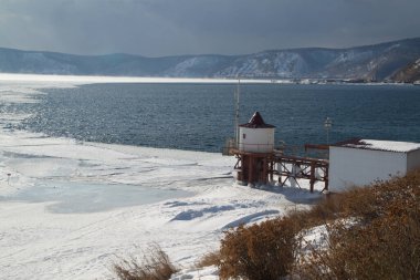 Scenic at the ice-free Angara River flows out of the frozen Lake Baikal. Melted ice floes on blue water.  Located Baikal lake , Listvyanka city in Russia. clipart