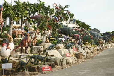 CHON BURI , THAILAND - SEPTEMBER  6 , 2023  : The beautiful dinosaur sculptures of various sizes in Dinosaur Valley at Nong Nooch Tropical Botanical Garden, another great tourist attraction. clipart