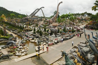 CHON BURI, THAILAND - 6 Eylül 2023: Nong Nooch Tropikal Bahçesi 'ndeki Dinozor Vadisi' nde güzel bir dinozor heykelinde ve çeşitli boyutlarda turistler.