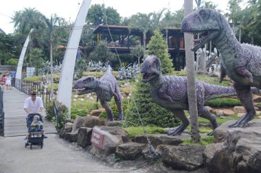 CHON BURI, THAILAND - 25 Eylül 2023: Nong Nooch Tropikal Bahçesi 'ndeki Dinozor Vadisi' nde çeşitli boyutlarda güzel dinozor heykelleri, başka bir büyük turistik ilgi alanı.