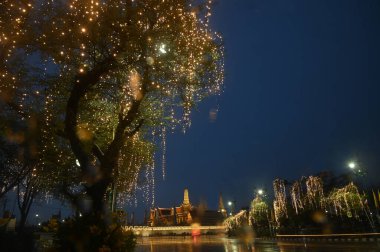 Rainy day on Sunset time of lights decorate at Wat Phra Kaew. This is a place of respect and tourism for Buddhists and tourists around the world. clipart