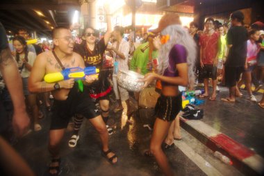 BANGKOK, THAILAND - 14 Nisan 2024: Songkran Günü (Tayland Yeni Yıl / Su Festivali) sokaklara su sıçratan turistler dans ederek, ateş ederek ve Silom yoluna su dökerek.