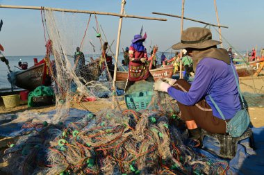 CHON BURI, THAILAND -HAZİRAN 18, 2025 Tayland yerel balıkçıları Na Jomtien Sahili, Pattaya 'da balık ve balık ağları topluyor. Taylandlı balıkçılar, geleneksel ahşap teknelerde ağlarla ya da tuzaklarla balık yakalıyorlar..