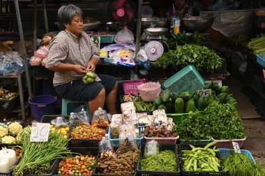 SAMUT SAKHON, THAILAND - 9 Eylül 2024: Kimliği belirsiz bir satıcı Mahachai İstasyonu 'nda sebze, meyve satıyor. Tren geldiğinde, rafları yerinde bırakıyor çünkü daha aşağıda....