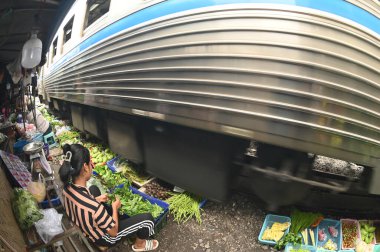 SAMUT SAKHON, THAILAND-SEPT 9, 2024: Meçhul bir satıcı Mahachai İstasyonu 'nda sebze, meyve satıyor. Tren geldiğinde, rafları yerinde bırakıyor çünkü daha aşağıda....