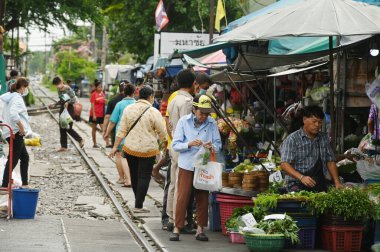 SAMUT SAKHON, THAILAND - 9 Eylül 2024: Kimliği belirsiz bir satıcı Mahachai İstasyonu 'nda sebze, meyve satıyor. Tren geldiğinde, rafları yerinde bırakıyor çünkü daha aşağıda....
