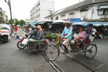 SAMUT SAKHON, THAILAND - 9 Eylül 2024: Kimliği belirsiz Asyalı bir erkek eski usul Tayland üç tekerlekli bisikletine biniyor, yolcuları Mahachai Tren İstasyonu 'ndan hedeflerine götürüyor..