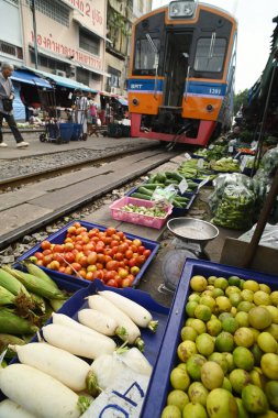 SAMUT SAKHON, THAILAND-SEPT 9, 2024: Meçhul bir satıcı Mahachai İstasyonu 'nda sebze, meyve satıyor. Tren geldiğinde, rafları yerinde bırakıyor çünkü daha aşağıda....