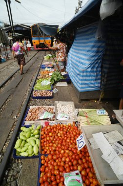 SAMUT SAKHON, THAILAND-SEPT 9, 2024: Meçhul bir satıcı Mahachai İstasyonu 'nda sebze, meyve satıyor. Tren geldiğinde, rafları yerinde bırakıyor çünkü daha aşağıda....
