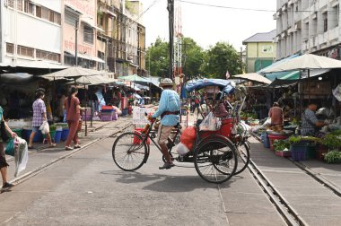 SAMUT SAKHON, THAILAND - 9 Eylül 2024: Kimliği belirsiz Asyalı bir erkek eski usul Tayland üç tekerlekli bisikletine biniyor, yolcuları Mahachai Tren İstasyonu 'ndan hedeflerine götürüyor..