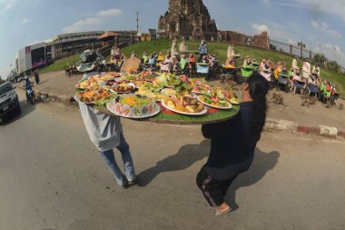 LOPBURI, THAILAND - 27 Kasım 2022: Maymunlar yerel meyve, sebze, salata, yumurta, tatlı yemeyi seviyor ki bu da insanları Phra Prang Sam Yod Tapınağı 'ndaki Maymun Partisi' nde teşekkür etmeye getiriyor..