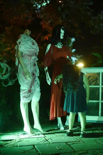 CHACHOENSAO, THAILAND - 31 Ekim 2024: Tanımlanamayan bir kız, korkunç hayalet bebeğin önünde kendini fotoğraflıyor. 2. Cadılar Bayramı etkinliğinde Somdej Phra Srinakarin parkında gece ortaya çıkıyor..