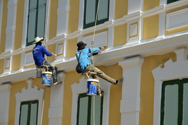 BANGKOK, THAILAND - 20 Nisan 2025: Büyük bir binanın duvarlarını asan, boyayan ve onaran isimsiz işçiler.