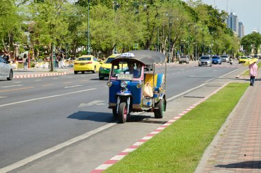 Üç tekerlekli bir araçta (tuk-tuk) bir erkek sürücü Tayland 'ın Bangkok kentindeki Wat Phra Kaew tapınağında bir yolcu bulur..