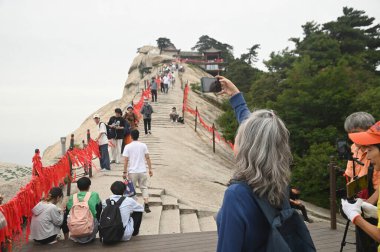 SHAANXI, ÇİN - 20 Haziran 2023: Huashan Dağı 'nda yürüyen tanımlanamayan turistler Çin' deki Beş Kutsal Dağdan biridir ve dik ve tehlikeli yolları nedeniyle dünyanın en tehlikeli dağ yollarından biridir..
