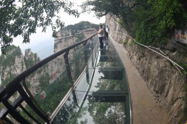 HENAN, Çin - 16 Haziran 2023: Tanımlanamayan turistler Çin 'in Henan Eyaleti' ndeki en güzel jeoloji parkı olan Yuntaishan Parkı 'nda cam gökyüzünde yürürler. Dünyanın ilk jeolojik miras bölgesi olarak listelenmiştir..